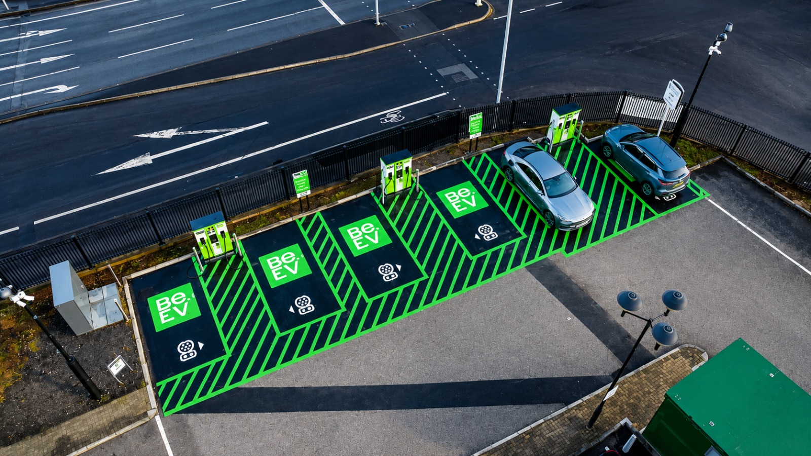 Aerial view of a multi-bay EV charging hub beside a public road